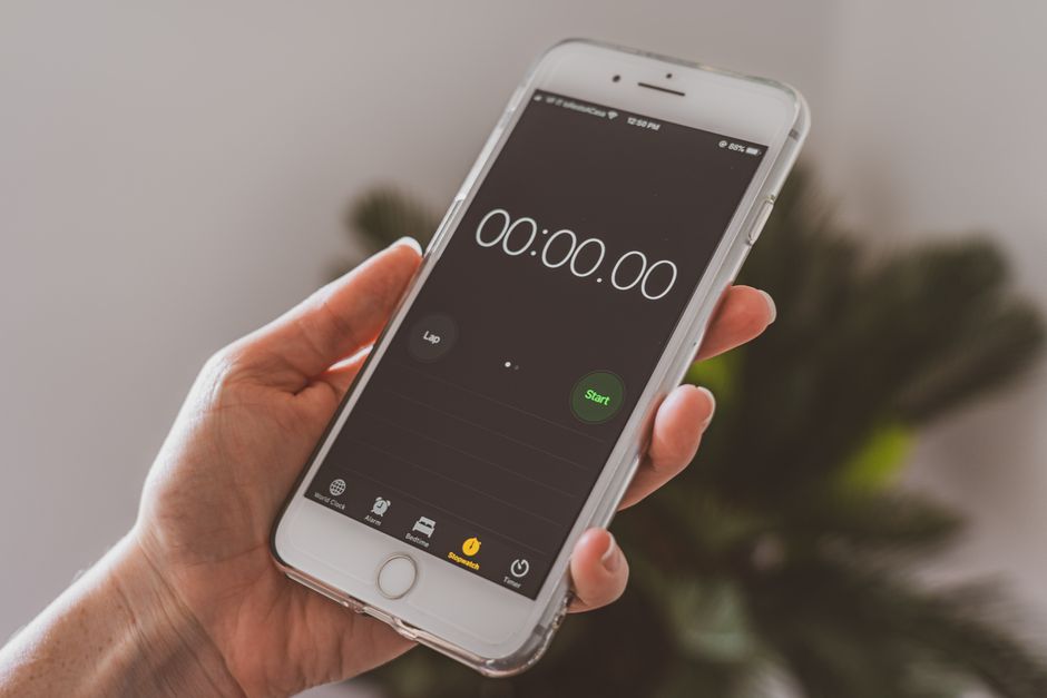 Smartphone held in hand displaying a stopwatch timer app.